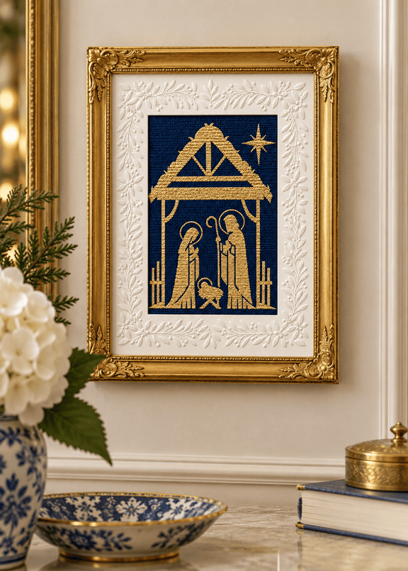 A Holy Night Nativity needlepoint in gold on navy, displayed in an ornate gold frame with a white botanical mat.